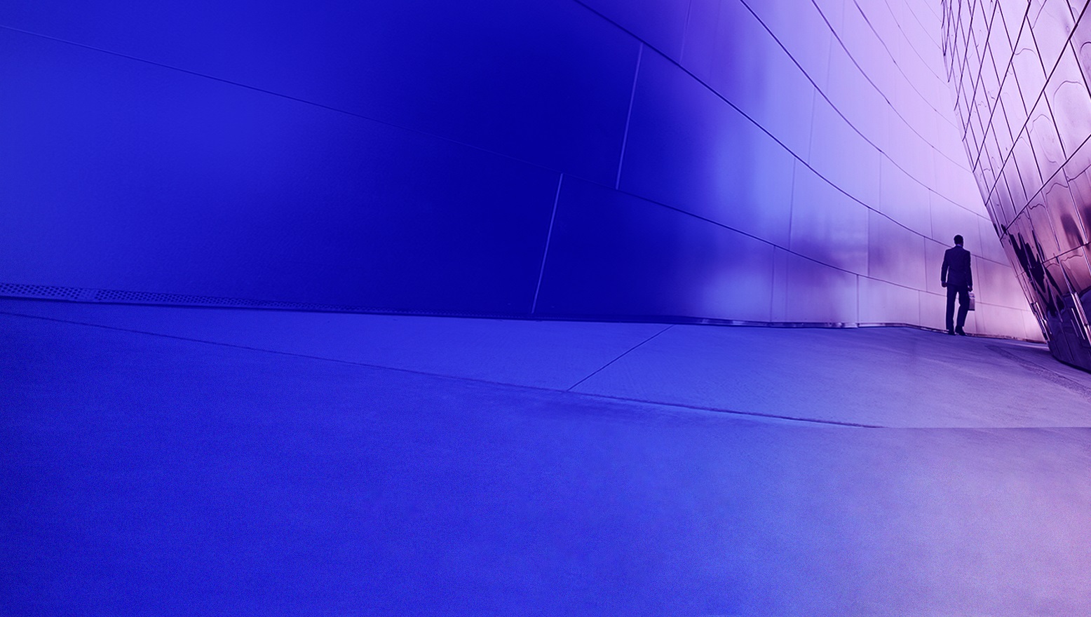 man walking down a hallway in a futuristic building 